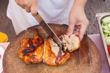 Chef are using Kitchen knife chicken grilled on wood block