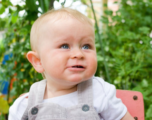 Funny 2-years old boy in a garden on a green background