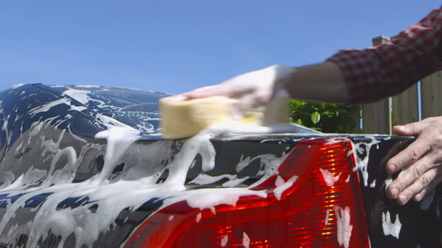 Care Care - Man washing a car using a sponge