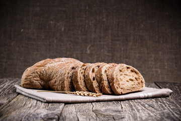 Tasty bread with wheat on wooden background.