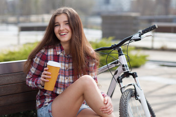 Fototapeta na wymiar Young woman drinking coffee on a bicycle trip