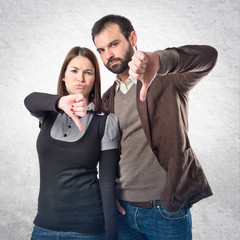 Couple with their thumbs down over white background