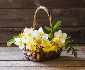 spring flowers in basket on wooden background