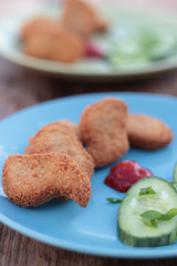 Chicken nuggets with sliced cucumber and ketchup.