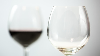 Glasses, one empty and one in background full of red wine