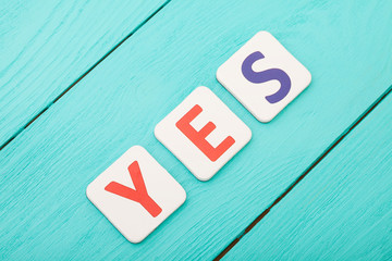 Word yes on blue wooden background. Top view