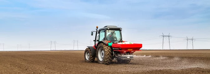 Cercles muraux Tracteur Farmer fertilizing arable land with npk fertilizer