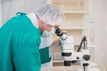 Scientist in scrubs using microscope