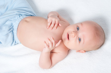 happy baby lying on white sheet