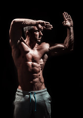 Fototapeta na wymiar Handsome muscular bodybuilder posing over black background
