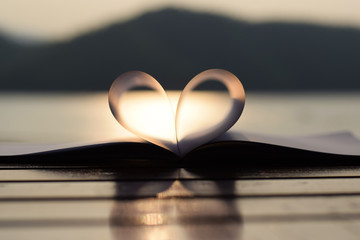heart shape from paper book at sunset (vintage background)