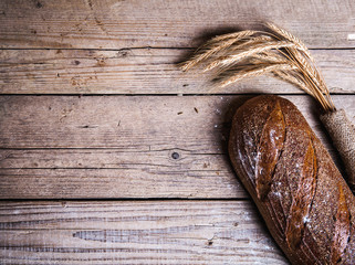 Rustic bread and wheat on an old vintage planked wood table.