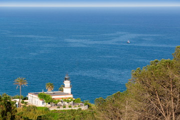 Fototapeta na wymiar old white lighthouse on the green hill above the sea