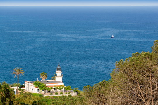 old white lighthouse on the green hill above the sea