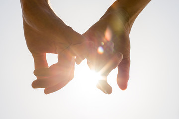 Couple holding hands toward the sun - Powered by Adobe