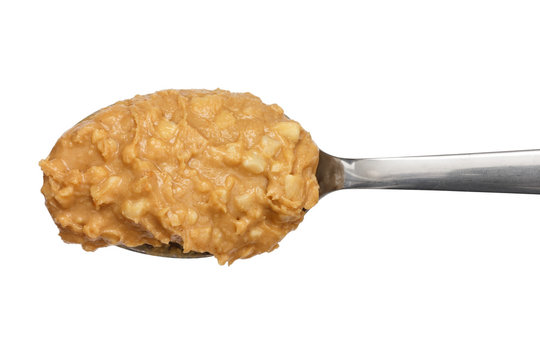 Crunchy peanut butter on metal spoon.