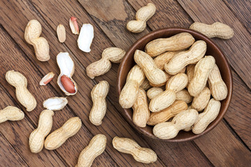 Rustic wood bowl of peanuts in shells. From above.
