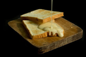 Sliced toast on chopping wood block and isolated on black background