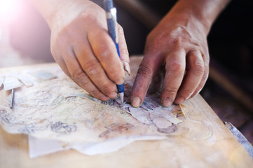 Vietnamese craftsman carving out and painting a floral pattern