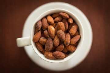 Fresh salted almonds in white ceramic glass (soft focus)