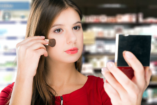 Young woman chooses make up in cosmetics shop.