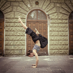 Attractive teen girl dancing outdoor in park against old buildin