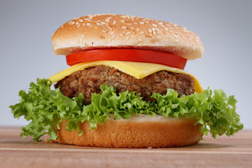 Hamburger with grilled meat and cheese on a wooden surface 

