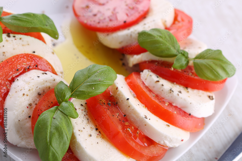 Sticker Tomato and mozzarella with basil leaves on a white plate