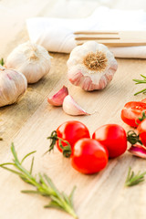 Fresh tomatoes, garlic and rosemary on the kitchen table.