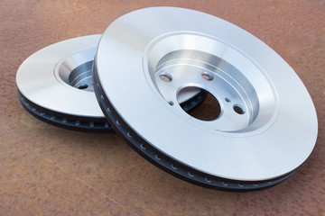 Two new ventilated disc brakes are on a rusty metal