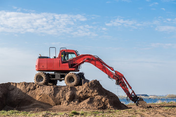Red excavator on a pile of sand