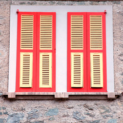 typical old red shutter windows in stone house, Italy.
