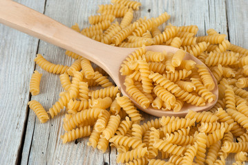 Uncooked fusilli pasta on old wooden table