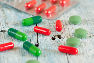Green and red pills on old wooden table