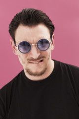 Handsome man portrait biting his lip and wearing sunglasses