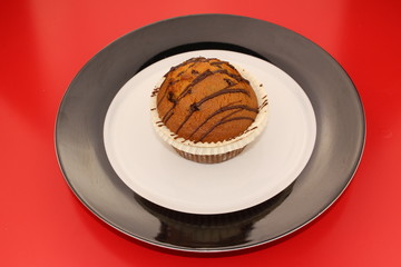 Isolated chocolate muffin on a black and white plate