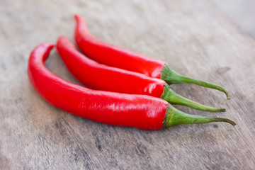 Hot red chili or chilli peppers over wooden background