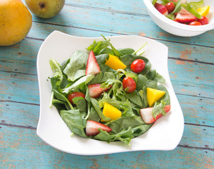 Vegetable and fruit salad arranged in a bowl on a wooden table