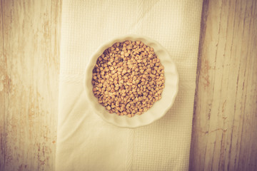 Buckwheat grains in white bowl. Studio shot with vintge mood
