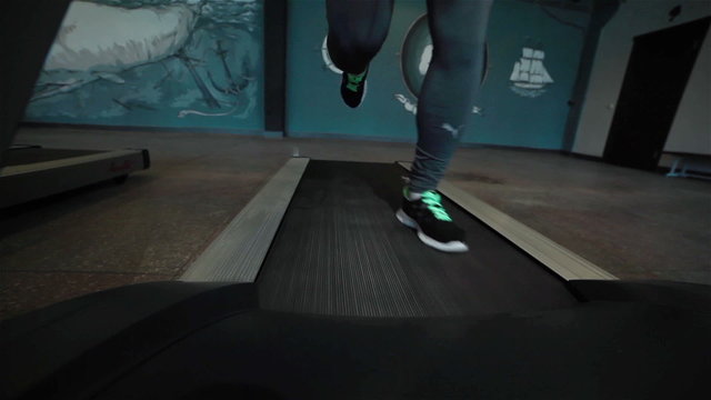 Frontal shot of a fit man exercising on treadmill. Close-up
