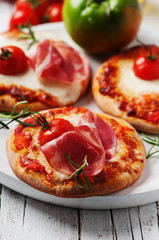 Mini pizza with mozzarella, prosciutto and tomato