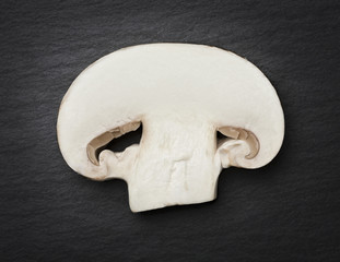 Fototapeta premium Cut champignon isolated on dark gray flagstone.