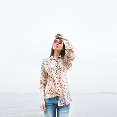 beautiful young hipster girl on the beach in a cold windy day