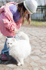 Cute little girl stroking white cat