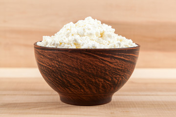 Fresh cottage cheese in a bowl on a wooden.