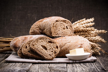 Tasty bread with wheat on wooden background.