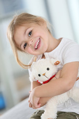 Portrait of cute blond little girl hugging teddy