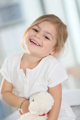 Fototapeta premium Portrait of cute blond little girl hugging teddy