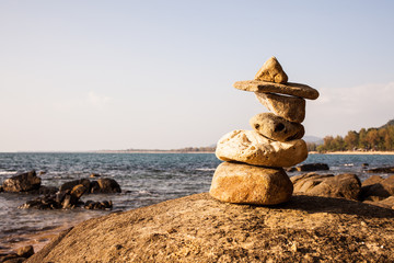 Fototapeta na wymiar Stack of pebbles on a big rock at the beach.