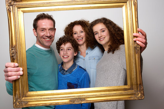 Happy Family Holding Picture Frame And Smiling
